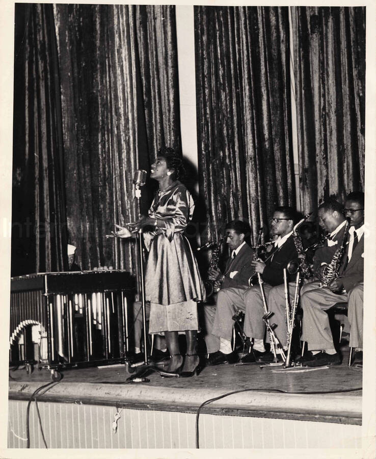 8 x 10 inch photograph. Unidentified vocalist performing with Lionel Hampton's orchestra at an U.S. Navy base