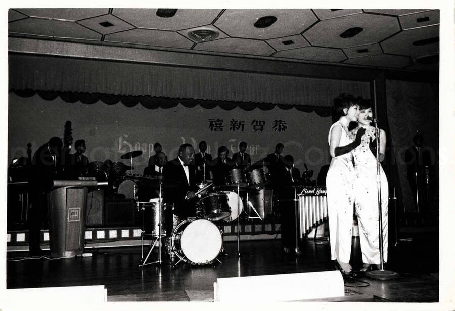 3 1/2 x 5 inch photograph. Lionel Hampton's band with two unidentified women dressed in Japanese costume, singing in Japan