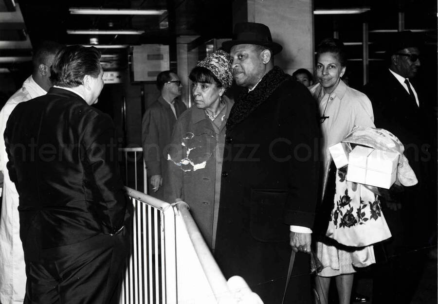 4 1/2 x 6 1/2 inch photograph. Gladys and Lionel Hampton are welcomed at an airport terminal [in Japan]