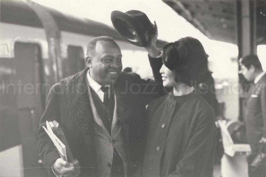 3 x 4 1/2 inch photograph. Lionel Hampton with unidentified woman on a train platform in Osaka, Japan
