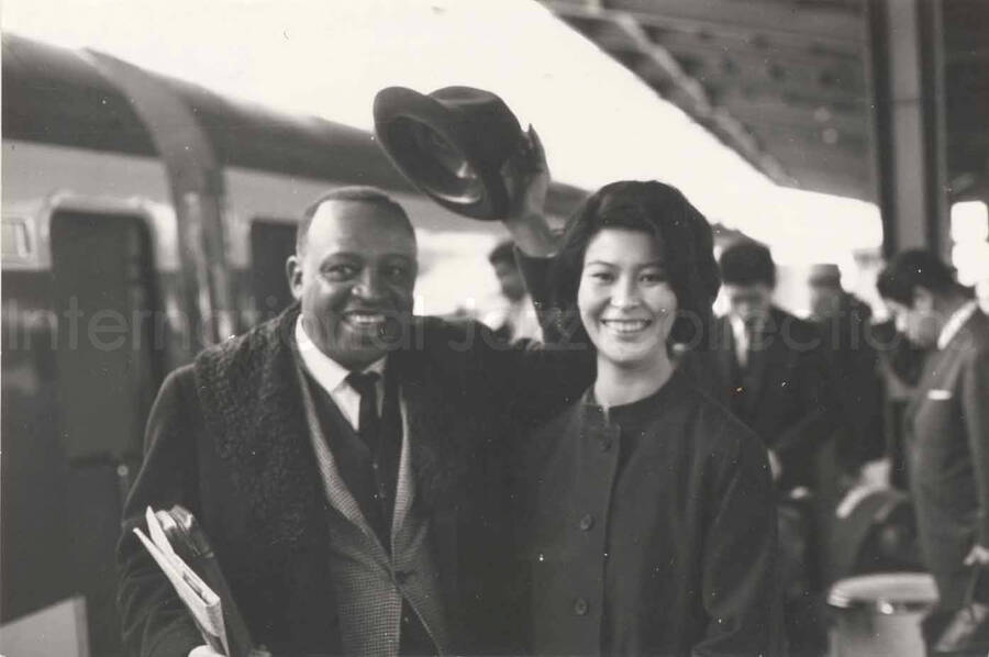 3 x 4 1/2 inch photograph. Lionel Hampton with unidentified woman on a train platform in Osaka, Japan