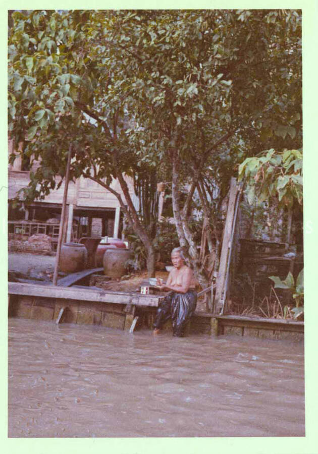 3 1/2 x 2 1/2 inch photograph. A person by the shore of a river