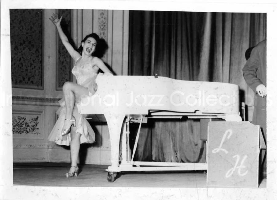 5 x 7 inch photograph. Unidentified woman dancing and singing on stage with Lionel Hampton's orchestra