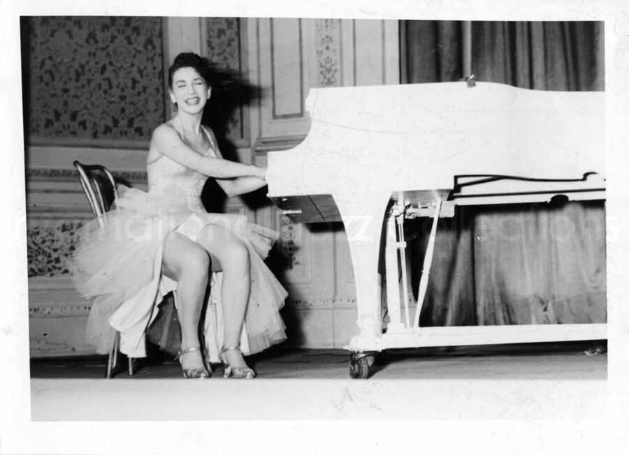 5 x 7 inch photograph. Unidentified woman dancing and playing the piano on stage with Lionel Hampton's orchestra