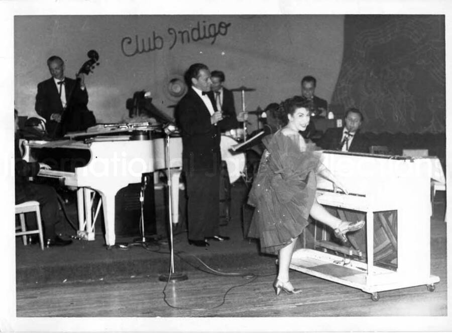 5 x 7 inch photograph. Unidentified woman dancing and playing the piano on stage at the Club Indigo