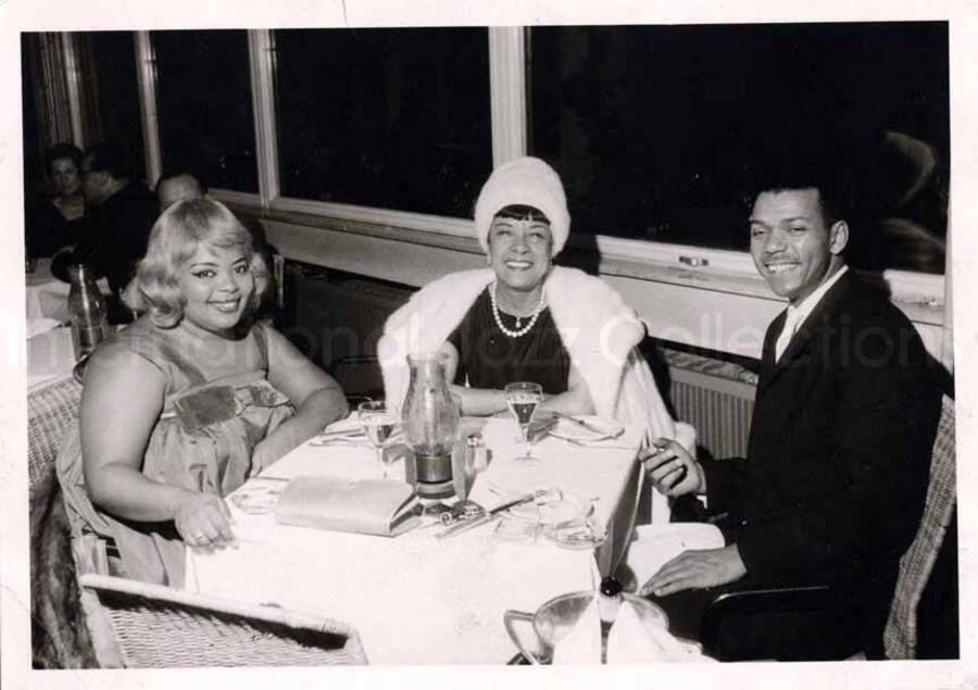 4 x 6 inch photograph in the format of postcard. Gladys Hampton and Leo Moore with unidentified woman at the restaurant of the Hilton Hotel in Berlin, Germany