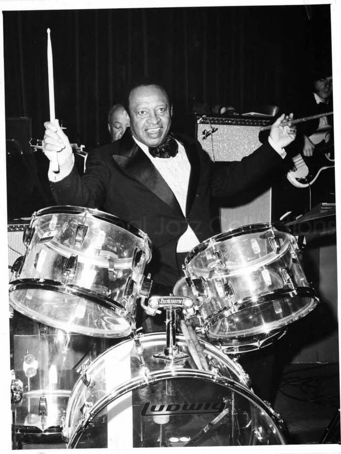 9 1/2 x 7 inch photograph. Lionel Hampton playing the drums with orchestra, which includes guitarist Billy Mackel