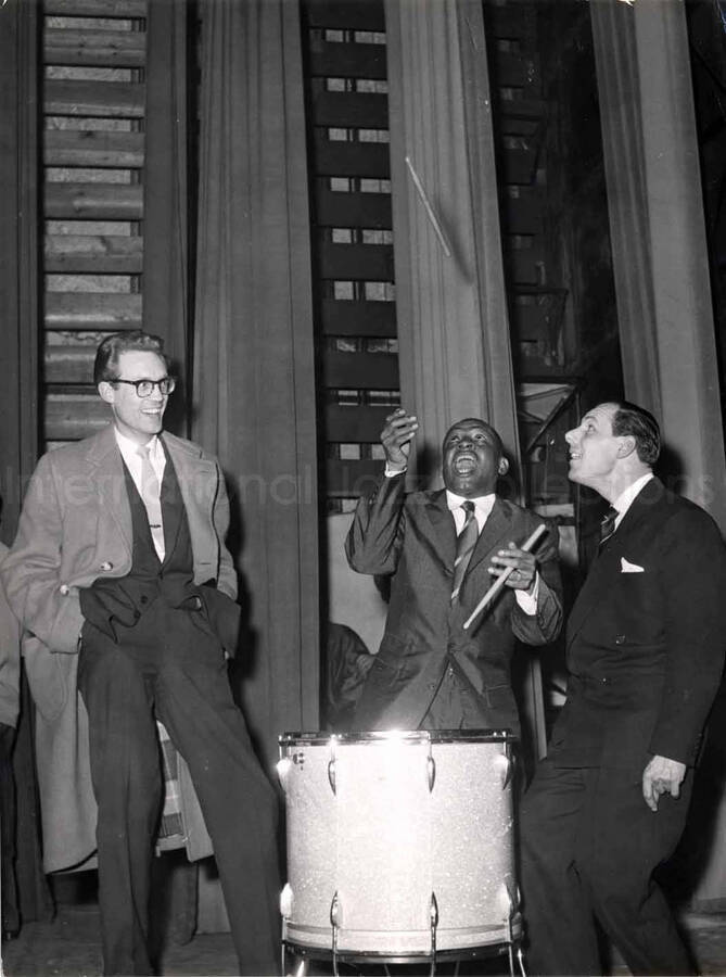 7 1/4 x 9 1/2 inch photograph. Lionel Hampton playing the drums with two unidentified men [in Paris, France]