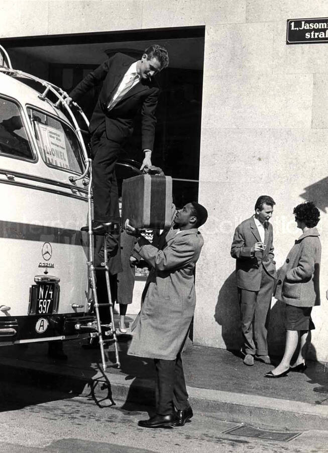 7 x 9 1/2 inch photograph. Unidentified men unloading luggage from a bus in Vienna, Austria