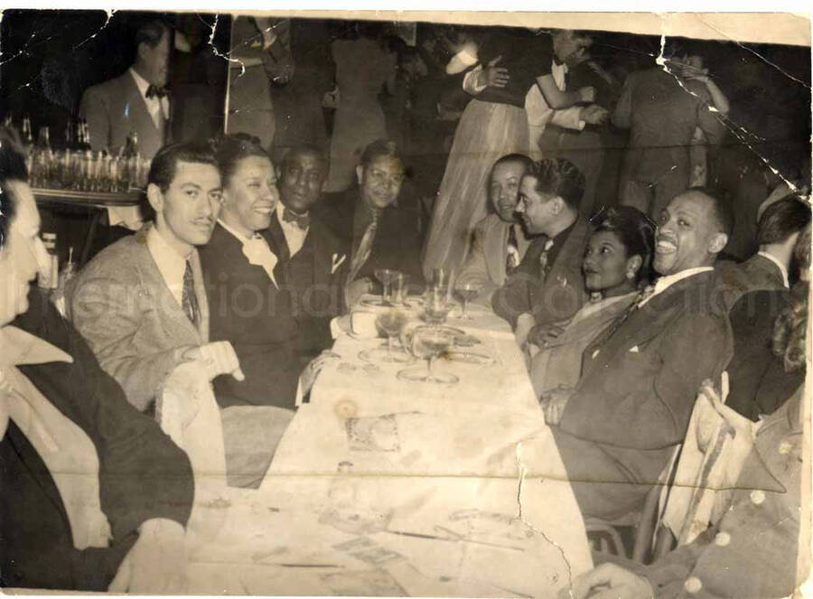 5 x 7 inch photograph. Gladys and Lionel Hampton with unidentified persons in a restaurant