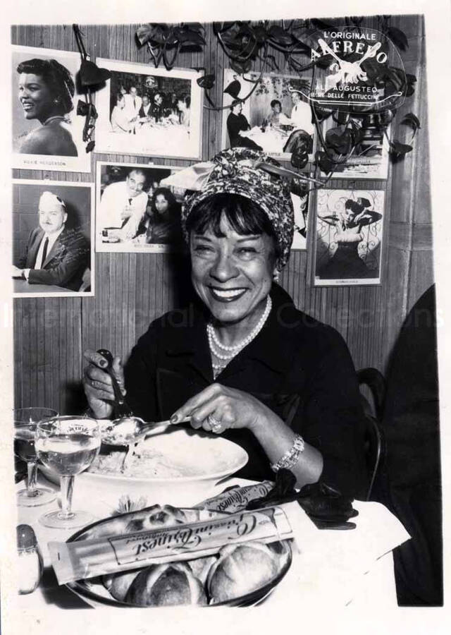 7 x 5 inch photograph. Gladys Hampton at the restaurant Alfredo, in Rome, Italy. Among the pictures of artists on the wall behind Gladys is one of Gladys and Lionel Hampton in the same restaurant in a different occasion (LH.III.0440)
