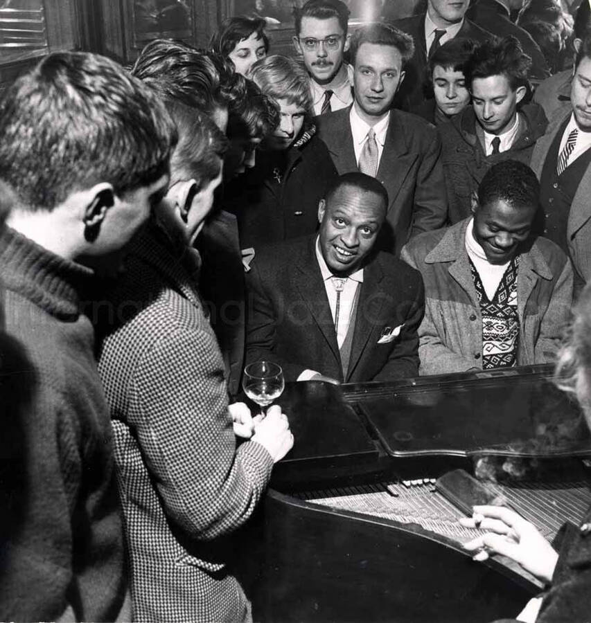 6 1/2 x 6 inch photograph. Lionel Hampton playing the piano surrounded by people