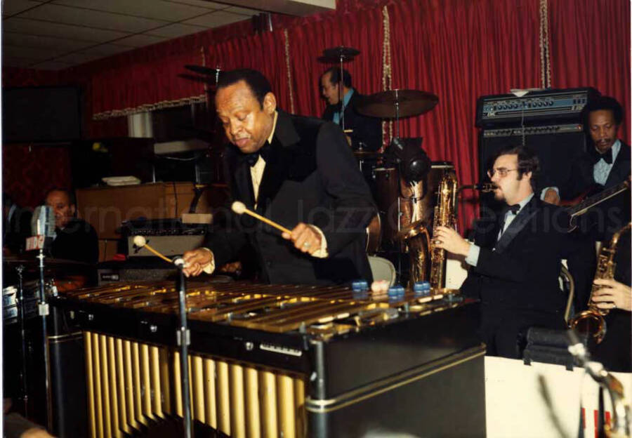 3 1/2 x 5 inch photograph. Lionel Hampton on vibraphone with band, among which is guitarist Billy Mackel