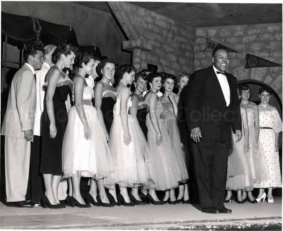 8 x 10 inch photograph. Unidentified choir and conductor. Observable on the wall in the background are banners that read: Williams