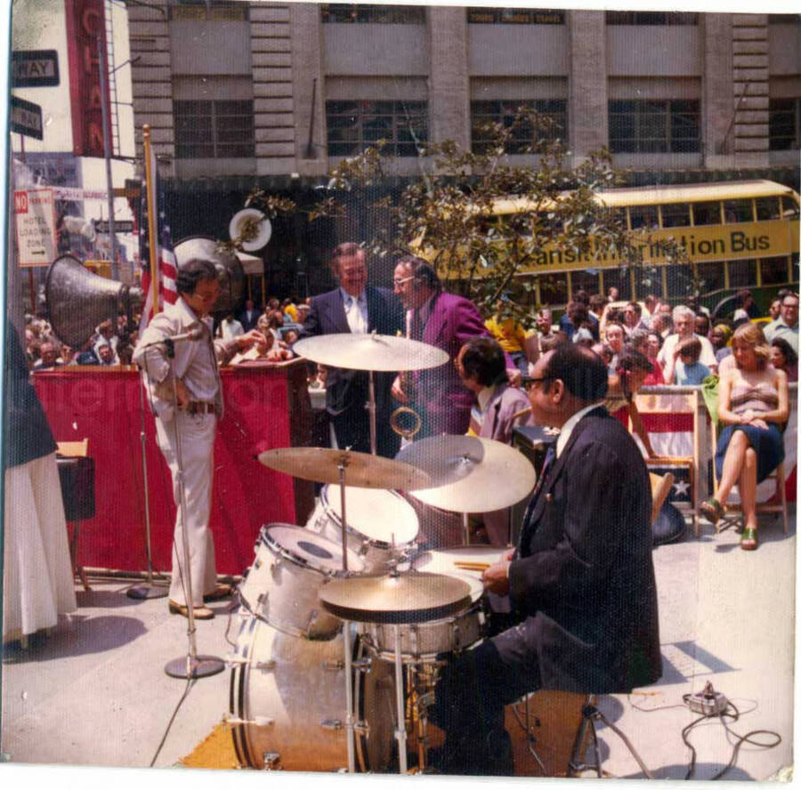 3 1/2 x 3 1/2 inch photograph. Lionel Hampton playing the drums. Handwritten on the back of the photograph: 52nd St. and 7th Avenue [New York]. The American flag can be seen in the background, suggesting it was during a political campaign