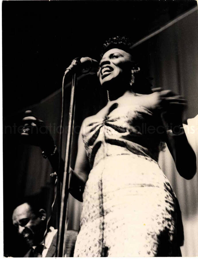 7 1/2 x 5 3/4 inch photograph. Unidentified vocalist with Lionel Hampton in the background