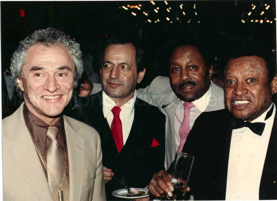8 x 11 inch photograph. Lionel Hampton with unidentified men at the Charles Hotel, Boston. From a scrapbook