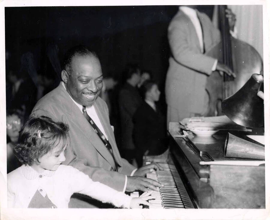 8 x 10 inch photograph. Count Basie on piano with a little girl