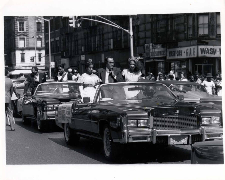 8 x 10 inch photograph. A car parade. The license plate of the first car is from New Jersey. The cars carry banners with names, including Charles Rangel and Sherry Williams