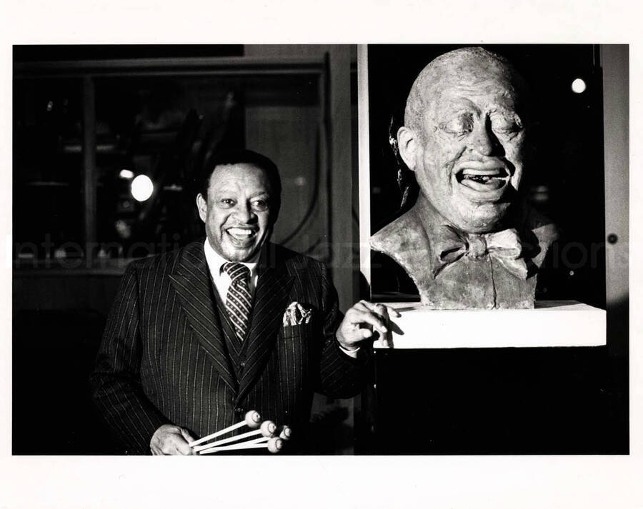 8 x 10 inch photograph. Lionel Hampton posing along his bust (sculpture)
