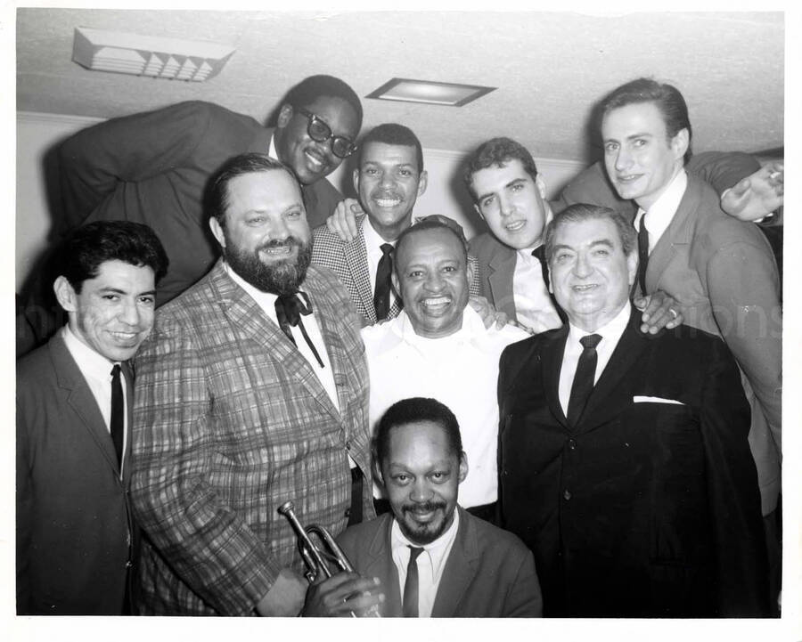 8 x 10 inch photograph. Lionel Hampton with Leo Moore, members of the band, and unidentified men