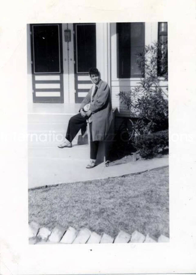 4 1/2 x 3 1/4 inch photograph. Unidentified woman sitting on the front steps of a house