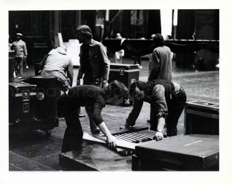 8 x 10 inch photograph. Group of men at work, apparently stage technicians loading orchestra equipment