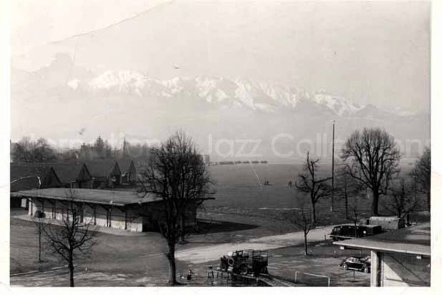 3 x 4 1/4 inch photograph. View of buildings with a snow-capped mountain in the background, probably in Switzerland. Handwritten on the back of the photograph: Emmi Schuppisser; Raterschen, Zurich