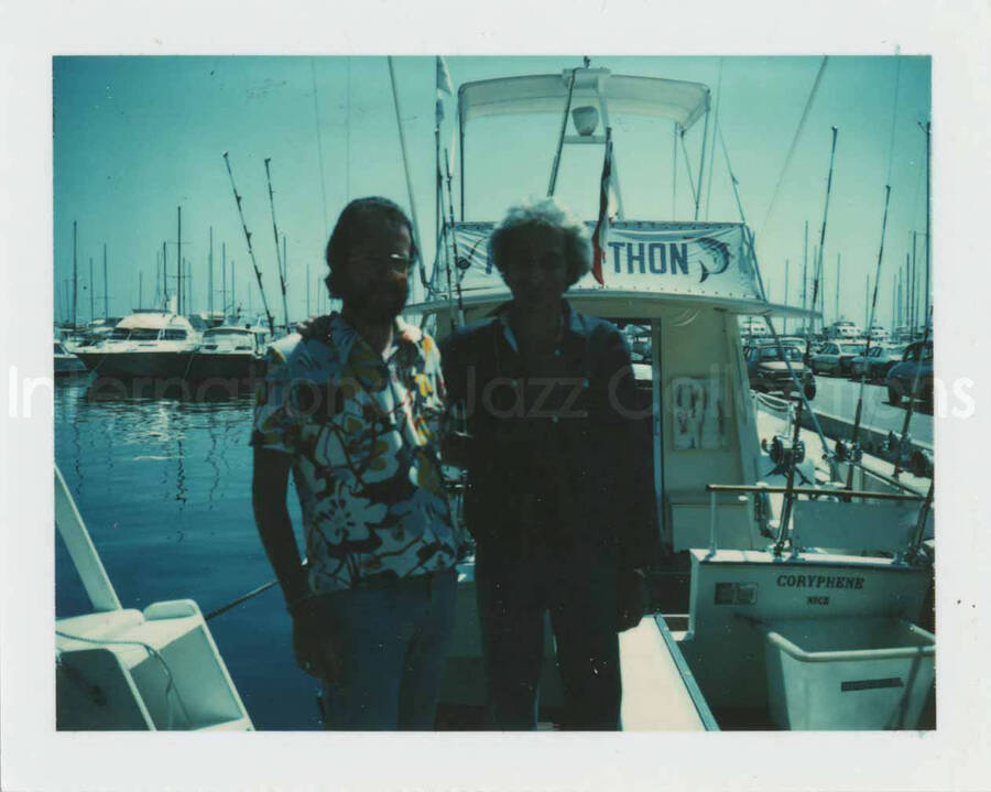 3 1/2 x 4 1/4 inch photograph. Jean Claude Forestier with Bill Titone standing on a deck. Observable in the background is a boat with the French words: thon, coryphene, Nice. [France?]