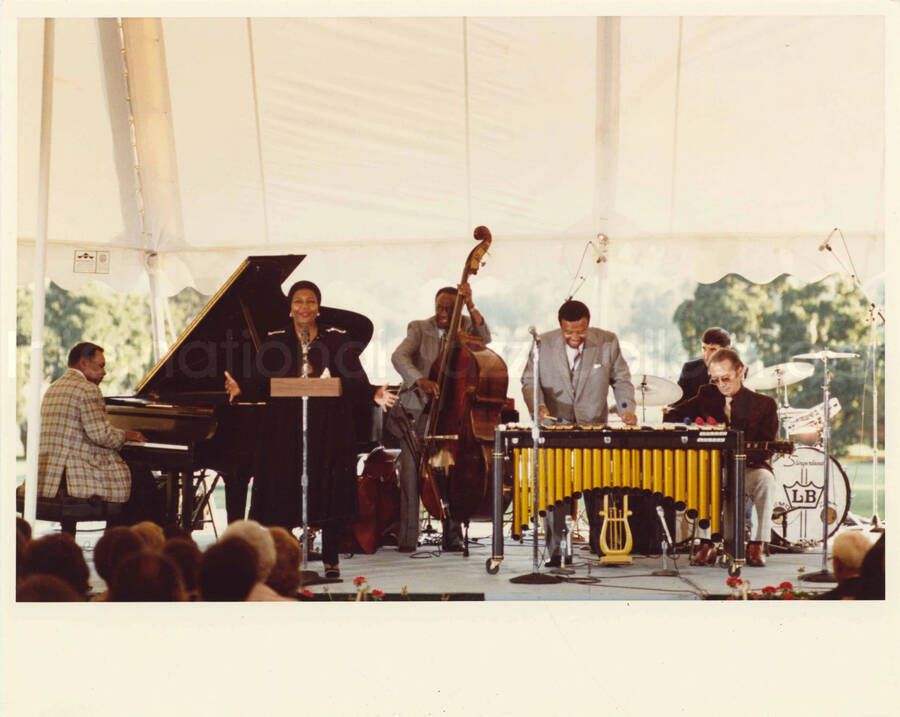 8 x 10 inch photograph. Lionel Hampton on vibraphone with Pearl Bailey and other musicians at an outdoor concert at the White House. This concert was aired January 27, 1982 on the public television special, Great Vibes! Lionel Hampton and Friends, as part of the Kennedy Center Tonight series