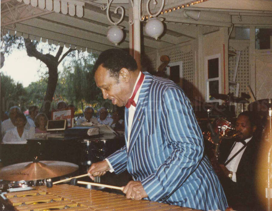4 x 5 inch photograph. Lionel Hampton performing on the vibraphone with band [at Disneyland]