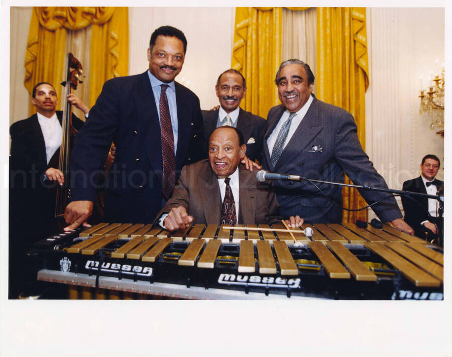 8 x 10 inch photograph. Lionel Hampton at the vibraphone with Jesse Louis Jackson, Sr., John Conyers, Jr., and Charles Bernard Rangel. [Lionel Hampton's 90th birthday?]