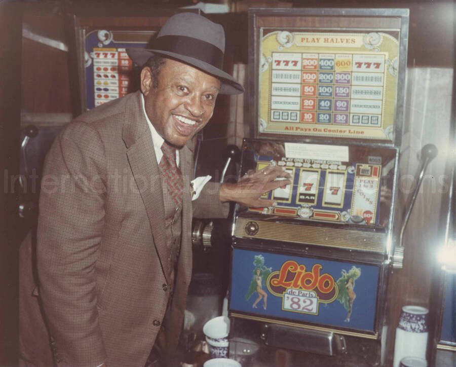 8 x 10 inch photograph. Lionel Hampton by a gambling machine. Accompanying this photograph is a portfolio from the Stardust Hotel and Casino - Lido, Las Vegas, Nevada