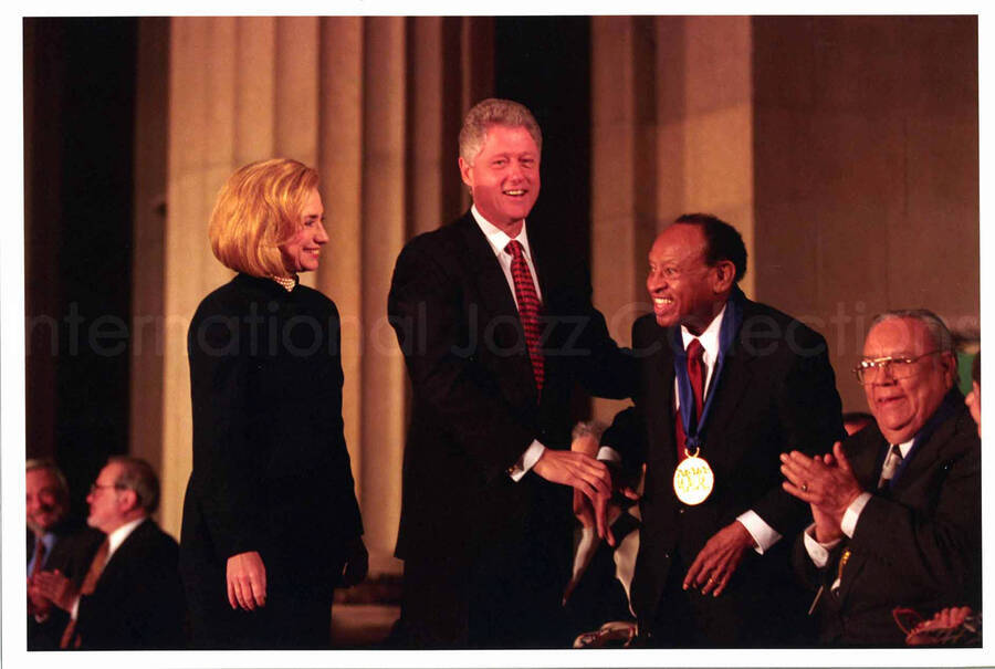 8 1/2 x 12 3/4 inch photograph; Hillary and Bill Clinton salute Lionel Hampton, awarded with the National Medal of Arts
