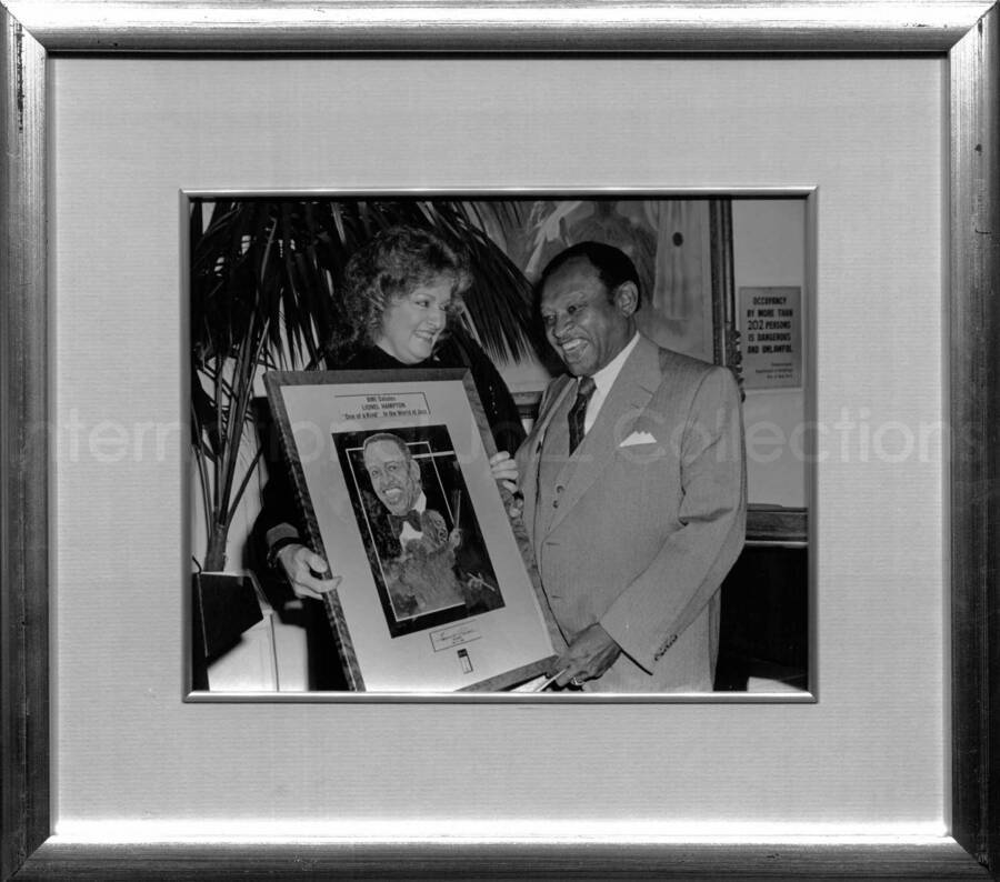 13 3/4 x 15 3/4 inch frame holding a black and white photograph. Has a label on the back from the BMI Archives. Lionel Hampton receiving a plaque from BMI President Frances W. Preston at the Tavern on the Green, New York
