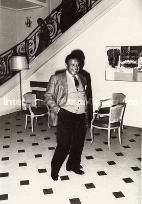 5 x 3 1/2 inch photograph. Hampton standing in the foyer of a building [Strasbourg, France?]. Sign on the wall is in French: J'ai vu le Conseil de L'Europe [Council of Europe]