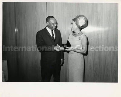 8 x 10 inch photograph. Lionel Hampton with Joan Crawford. She is holding a medal from Playboy
