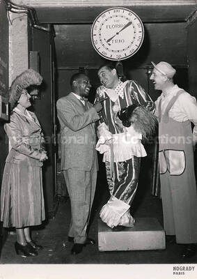 7 x 5 inch photography. Lionel Hampton with three unidentified persons in costumes, one of whom is on a weight scale that reads: The Florida Trio
