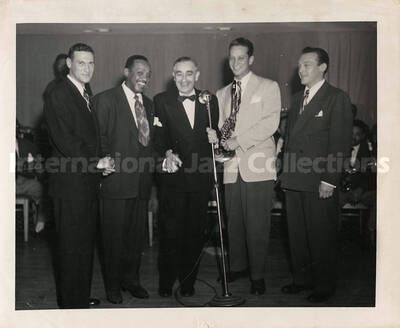 8 x 10 inch photograph. Lionel Hampton with Hirsh de La Viez and others. Handwritten on the back of the photograph: Left to right, Arnold Fine, drama Editor, Washington Daily News; Hampton; Hirsh De La Viez, Pres. Washington Music Guild[?]; Sam Donahue; Freddie Slack