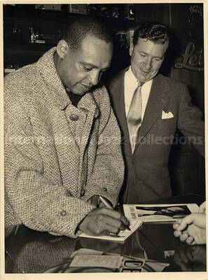 9 x 7 inch photograph. Lionel Hampton autographing for fans, in a store [abroad?]