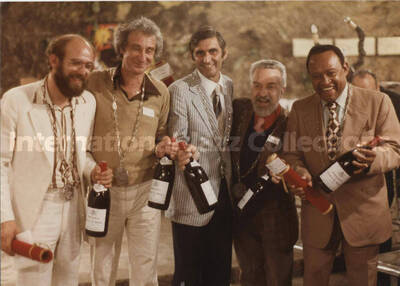 5 x 7 inch photograph. Lionel Hampton, Bill Titone, and three unidentified men holding bottles of wine, in France. They are wearing medals of the Commanderie des Costes du Rhône
