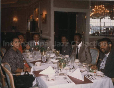 3 1/2 x 4 1/2 inch photograph. Lionel Hampton sits at a dinner table with unidentified persons