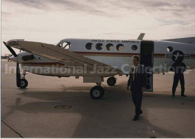 3 1/2 x 5 inch photograph. An unidentified man walks from a US Marines airplane