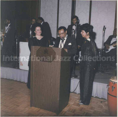 3 1/2 x 3 1/2 inch photograph. Lionel Hampton with [Pat Williams] and an unidentified woman, in a ceremony at the Garden City Hotel