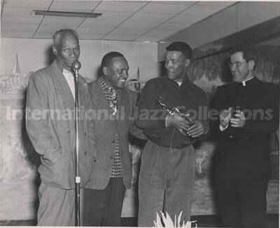 8 x 10 inch photograph. Lionel Hampton with three unidentified men, including a man wearing religious dress. One of the men is holding a trophy