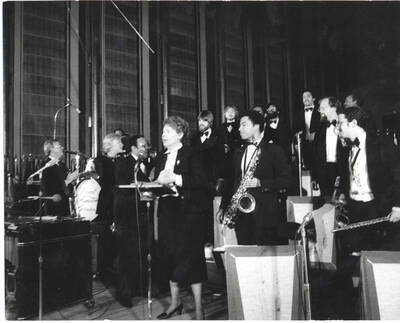8 x 10 inch photograph. Lionel Hampton,  Jeane Jordan Kirkpatrick, and orchestra, on the occasion of his receiving a plaque from the United States Mission that appointed him as Ambassador of Music to the United Nations
