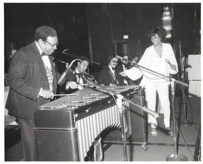 8 x 10 inch photograph. Lionel Hampton on vibraphone with unidentified woman, on the occasion of his receiving the Henri M. Deas Award for Community Service presented by the Opportunities Industrialization Center of New York