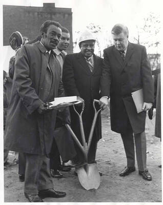 10 x 8 inch photograph. Lionel Hampton with unidentified men holding a shovel with three handles at the ground breaking ceremony of the Lionel Hampton Houses