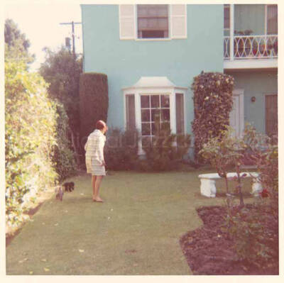 Gladys Hampton walking her dog in the yard of the Hampton home. 3 1/2 x 3 1/2 inch photograph.