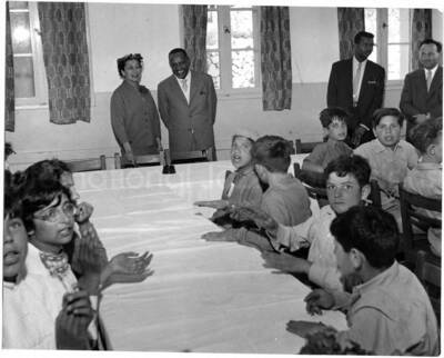 5 x 6 inch photograph. Lionel Hampton with unidentified persons visiting with children [at Swiss Village] in Israel. Seen in the background is Leo Moore